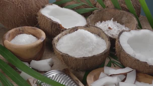 新鮮なオープンココナッツとココナッツフレーク スライス ココナッツの葉は木のテーブルでゆっくり回転しています — ストック動画