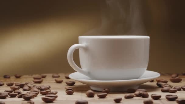 コーヒー豆が付いている木のテーブルのホワイト カップのコーヒーおよび上昇の蒸気はゆっくり回ります あなたのプロジェクトのための素敵な暖かいコーヒーの背景 — ストック動画