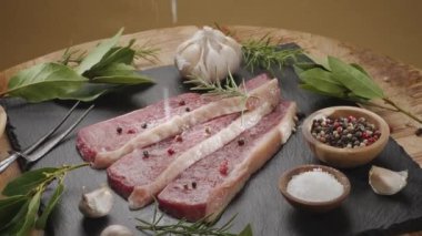 Gri bir tezgahın üzerinde baharat ve otlarla dilimlenmiş üç parça picanha bifteği yavaşça çerçevede döner. Geleneksel Portekiz yemekleri.