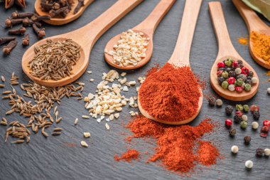 Gri taş masadaki tahta kaşıklarda çeşitli baharatlar, projeleriniz için harika yemek arkaplanı..