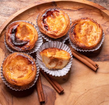 Pastel de nata turtaları ve ahşap tepside tarçın çubukları. Üst görünüm.