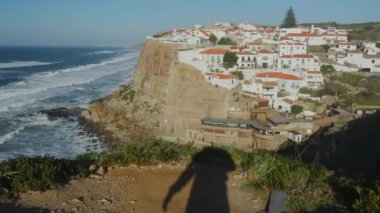 Okyanus kıyıları gün batımında Azenhas 'ta Mar, Portekiz, Sintra yakınlarındaki Colares bölgesinde. Azenhas do Mar Portekiz 'de popüler bir turizm merkezidir. Kırmızı çatıları olan güzel beyaz evler görünür..