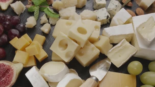 Verschiedene Käsesorten Mit Früchten Minze Nüssen Und Käseschneidemessern Rotieren Langsam — Stockvideo