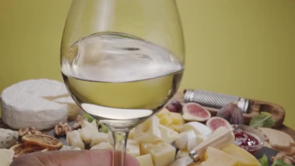 フルーツ ミント ナッツ チーズカッティングナイフの様々なスライスチーズと白ワインの試飲がゆっくりフレームで回転します あなたのプロジェクトのための素晴らしいチーズとワインの背景 — ストック動画