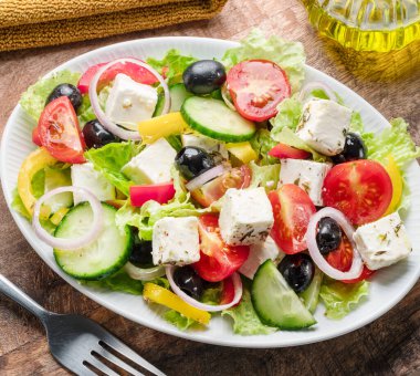 Greek salad on  wooden table served and ready to eat. clipart
