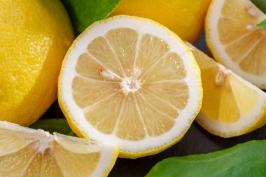 Gri taş bir masada dilimler ve limon yapraklarıyla olgun limon meyveleri. Projeleriniz için güzel meyve arkaplanı.. 