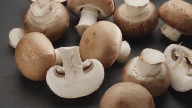 Şampiyonların dilimleriyle olgunlaşmış kraliyet şampiyonu mantarları gri taş bir masanın üzerinde yavaşça hareket ediyor. Projelerin için güzel bir sebze arka planı. Makro video çekimi.