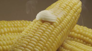 Bir parça tereyağı olgun haşlanmış mısır koçanı boyunca yavaşça hareket eder. Projelerin için güzel bir yemek geçmişi var. Makro video çekimi. 