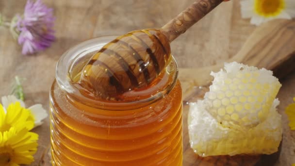 一滴滴蜂蜜慢慢地从一个木制的蜂蜜搅拌器流入一个蜂蜜碗 动作缓慢 为你的任何一个项目提供一个完美的食物背景 — 图库视频影像