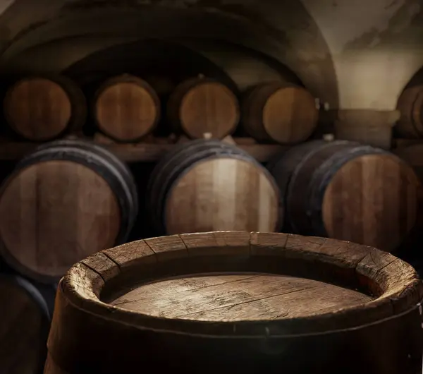 Empty top of  wooden barrel and  wood barrels in cellar at the background. Sun ray falling down to it surface. Placement for your product.