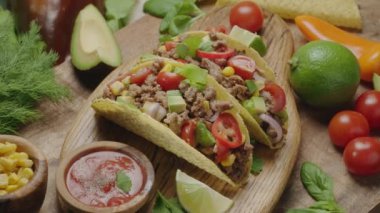 İki kişi tahta tahtada taze otlar ve sebzelerle çevrili tacolarla karşılaşır. Geleneksel Meksika yemekleri saat yönünde yavaşça döner..