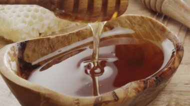 Bal damlaları yavaşça tahtadan bal kabından bal kabına akıyor, yakın çekim, yavaş çekim. Projeleriniz için mükemmel bir yemek geçmişi..