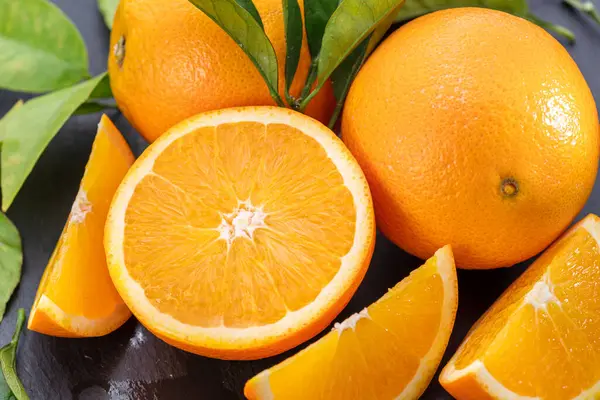 Reife Orangenfrüchte Mit Scheiben Und Orangenblättern Auf Einem Grauen Steintisch Stockbild