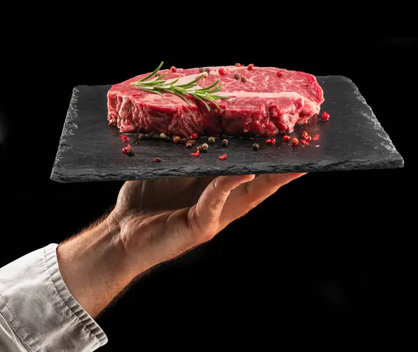 Cook Hält Graphit Servierbrett Mit Rohem Ribeye Steak Auf Schwarzem Stockbild