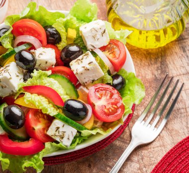 Greek salad on  wooden table served and ready to eat. clipart
