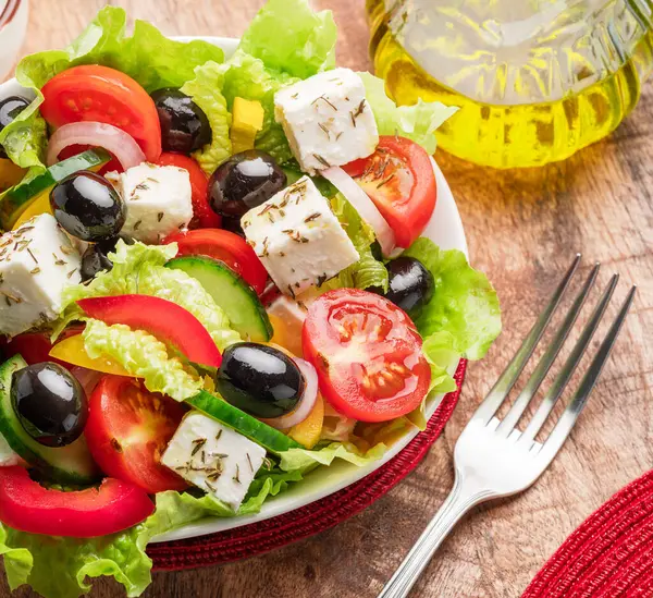 木のテーブルにギリシャのサラダが提供され 食べる準備ができました ロイヤリティフリーのストック画像