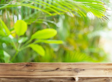 Empty wooden board or table top and blurred green bamboo culms. Place for your product display. 
