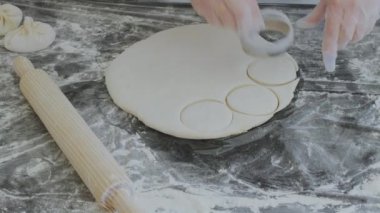 Hamur köftesi, khinkali veya turta için hamur hazırlıyorum. Hamuru un kaplı bir oklavayla uzatıyorum..