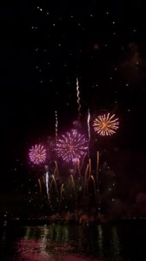 Muhteşem havai fişek gösterisi görüntüleri. Gece gökyüzünde patlayan renkli kıvılcımlar ve alevler. Dikey video.