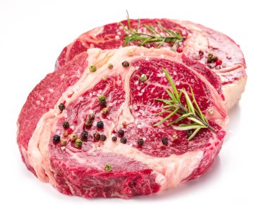 Beyaz arka planda pişmeye hazır baharatlı ve otlu çiğ biftek..