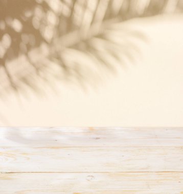 Kumlu duvardaki yaprakların bulanık gölgesi ve ön plandaki masanın üstü. Yaz konsepti.