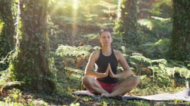 Kadın doğada yoga yapıyor. Rahatlamak için yavaşça oturun..