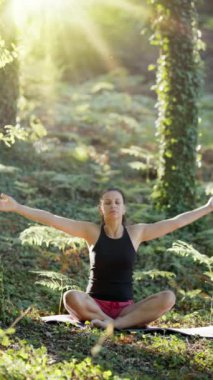 Kadın doğada yoga yapıyor. Rahatlamak için yavaşça oturun..