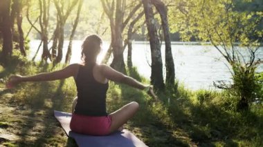 Kadın doğada yoga yapıyor. Rahatlamak için yavaşça oturun..