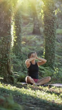 Kadın doğada yoga yapıyor. Rahatlamak için yavaşça oturun..