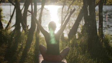 Kadın doğada yoga yapıyor. Rahatlamak için yavaşça oturun..