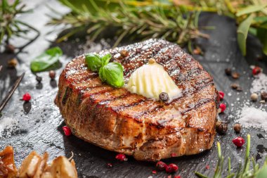 Erimiş tereyağlı ızgara lezzetli pirzola bifteği. Biftek siyah tabakta servis edilir.. 