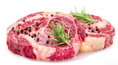 Beyaz arka planda pişmeye hazır baharatlı ve otlu çiğ biftek..