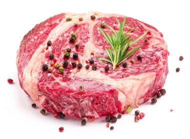 Beyaz arka planda pişmeye hazır baharatlı ve otlu çiğ biftek..