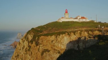 Portekiz 'deki deniz fenerine bakan Cape Cabo Da Roca' da Atlantik Okyanusu 'nda güzel bir gün. Avrupa 'nın en batı noktası, Temmuz 2023. Yavaş kamera hareketi geriye - yaya yürüyüşü taklidi.