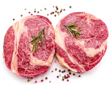 Beyaz arka planda pişmeye hazır baharatlı ve otlu çiğ biftek..