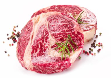 Beyaz arka planda pişmeye hazır baharatlı ve otlu çiğ biftek..