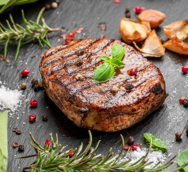 Izgara lezzetli pirzola bifteği ve siyah tabakta biraz baharat ve otlar. Düz yatıyordu.