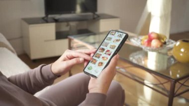 İnternette akıllı telefon kullanarak bir restoranda suşi sipariş etmek. Kadın internet üzerinden bir restoranın internet menüsünden akıllı telefondan bir uygulama kullanarak suşi seçiyor..