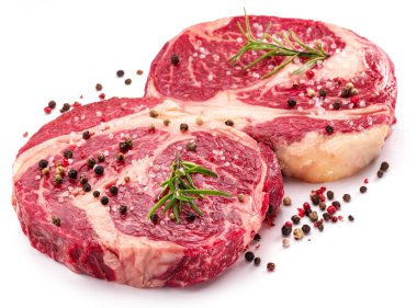 Beyaz arka planda pişmeye hazır baharatlı ve otlu çiğ biftek..