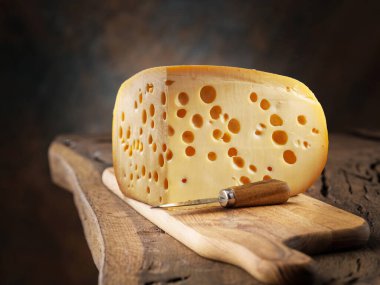 Masadaki tahta kesme tahtasının üzerindeki Emmental peyniri bloğu.