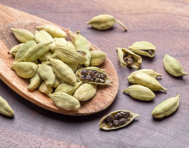 Tahta bir masada tahta kaşıkta kakule baharatları, sıcak şarap malzemesi, makro görüntü. Projeleriniz için harika baharatlar arkaplanı.