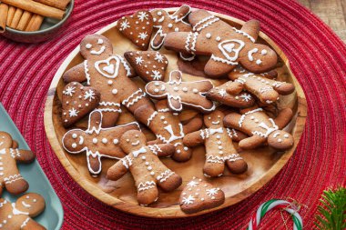 Gingerbread men, christmas cookies decorated with royal icing on blue plate, top view. clipart