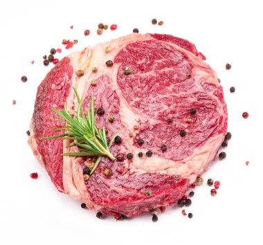 Beyaz arka planda pişmeye hazır baharatlı ve otlu çiğ biftek..