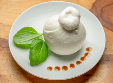 Bir top mozzarella ya da ahşap arka planda taze fesleğen yapraklı burrata peyniri..