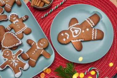 Gingerbread men, christmas cookies decorated with royal icing on blue plate, top view. clipart