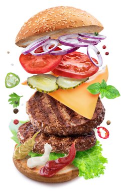 Beyaz arka planda havada süzülen sebzeli ve peynirli etli köfte burgeri. Dosya kırpma yolları içeriyor.