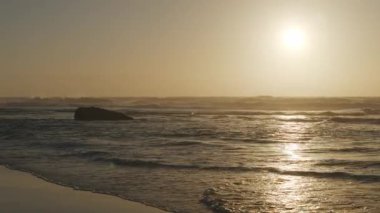 Atlantik Okyanusu 'nun Adraga plajı gün batımında, Sintra Portekiz. Güneş, su yüzeyine parlak bir yol ile yansıdı. Yavaş çekim videosu.