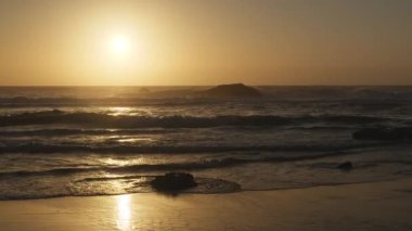 Atlantik Okyanusu 'nun Adraga plajı gün batımında, Sintra Portekiz. Güneş, su yüzeyine parlak bir yol ile yansıdı. Yavaş çekim videosu.