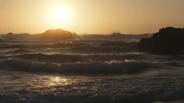 Atlantik Okyanusu 'nun Adraga plajı gün batımında, Sintra Portekiz. Güneş, su yüzeyine parlak bir yol ile yansıdı. Yavaş çekim videosu.