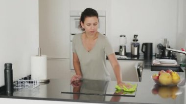 Kadın mutfak tezgahını, elektrikli sobayı ya da elektrikli ocağı temizliyor. Yavaş çekim görüntüleri. 